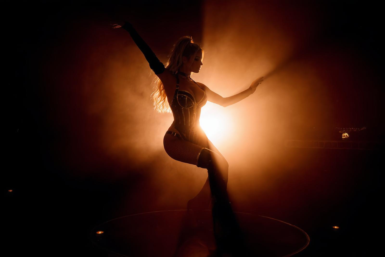 A performer silhouetted against a warm stage light