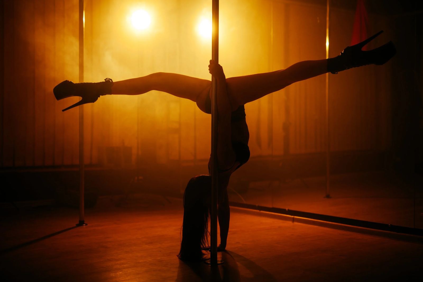 A performer on the pole, lit from behind