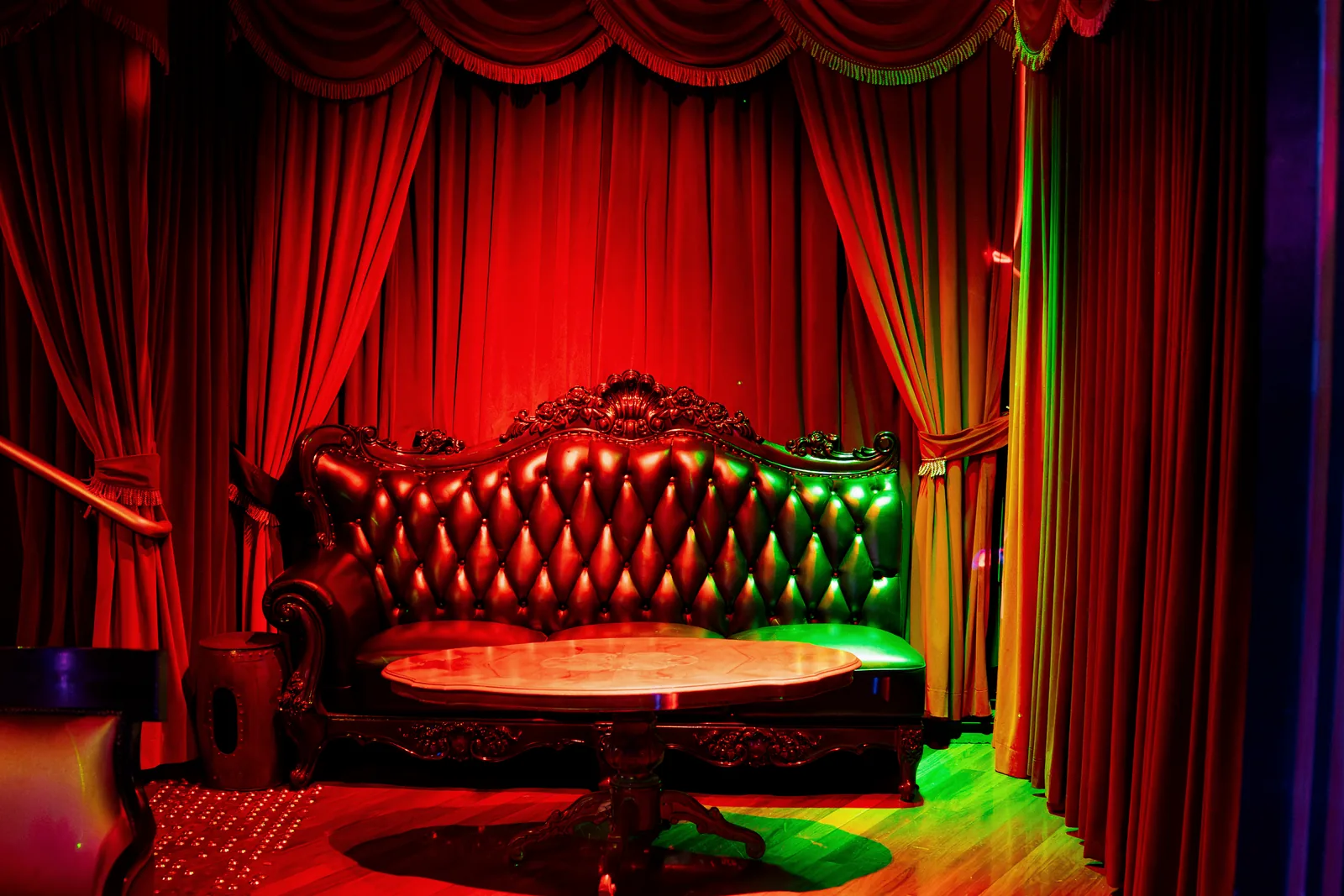 A carved tufted lounge and marble table against the back wall