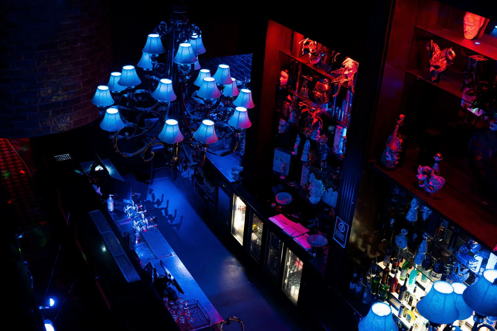 A chandelier above the Venetian mask collection on the bar shelves