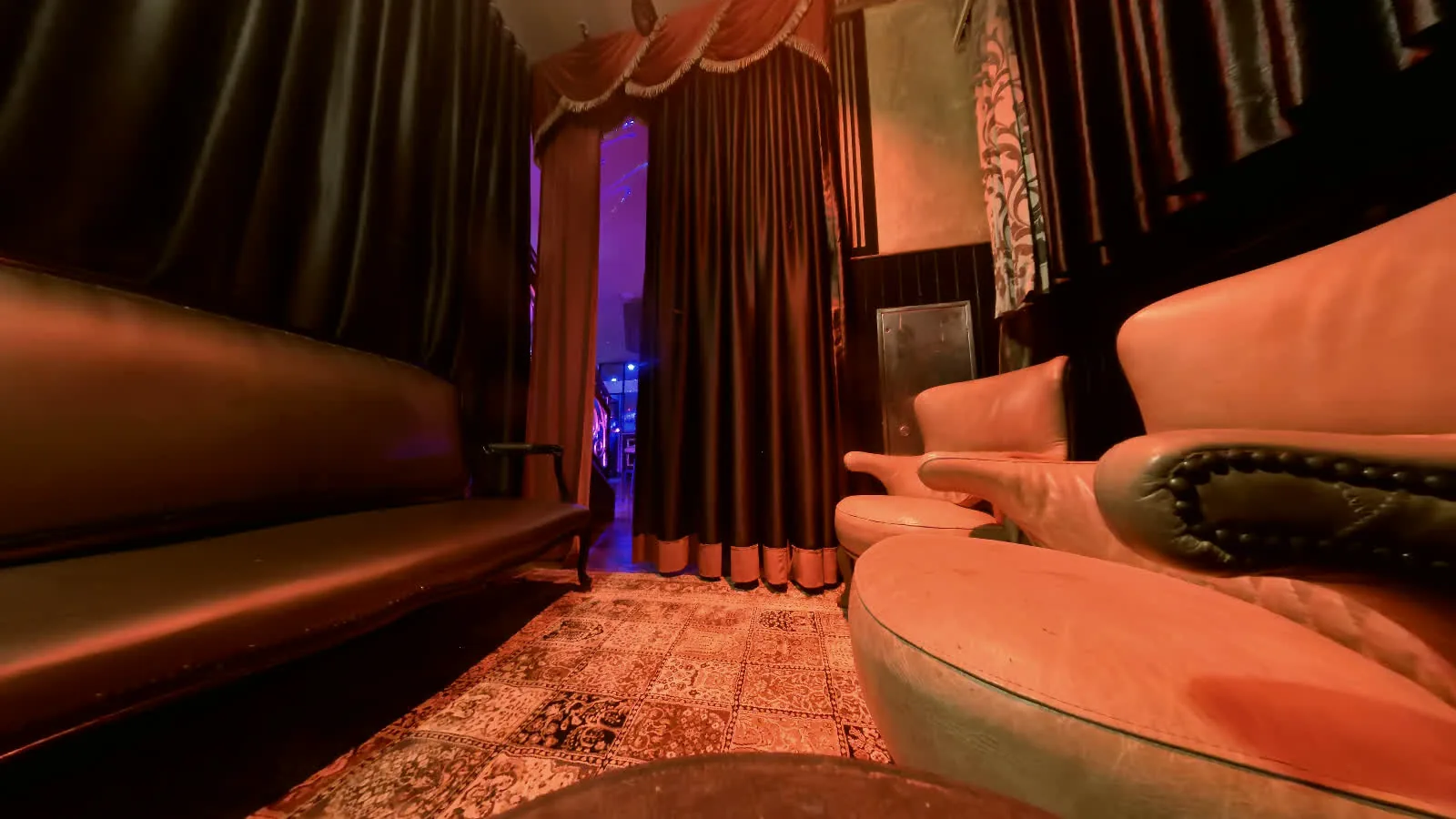 A leather lounge and two pale club chairs behind the curtain of the Level One private room